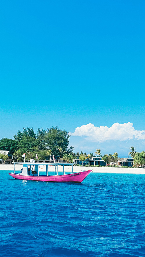 美しい南国の白い砂浜と青い海に浮かぶ鮮やかなピンク色のボート