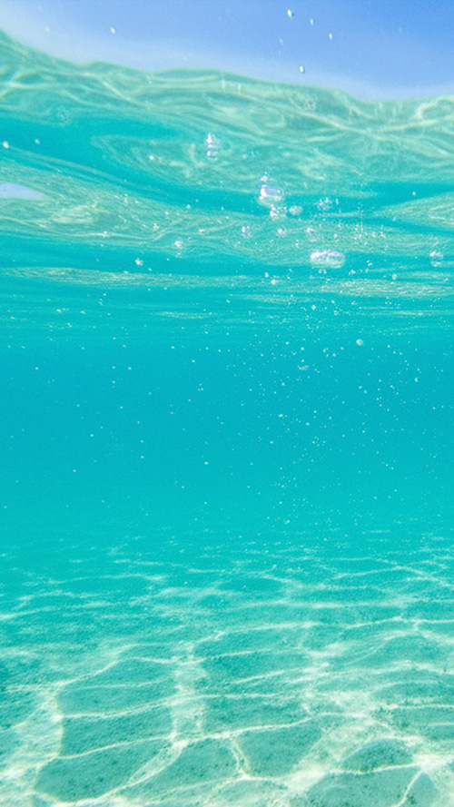 TikTok/YouTubeショートの背景にも使えるおしゃれな画像：太陽光が差し込む透き通った海中を立ち昇る気泡と水面の揺らぎ